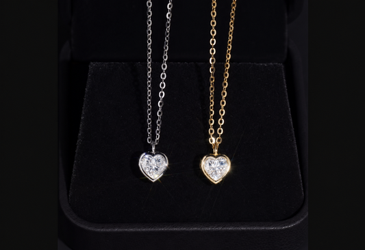 Silver and gold heart-cut moissanite pendant necklaces on black velvet